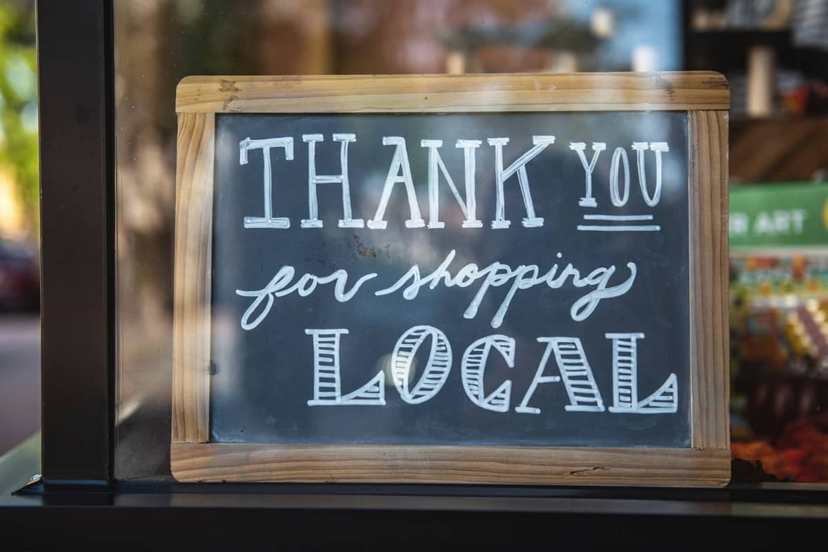 A chalkboard sign in a shop window reading "Thank you for shopping local"