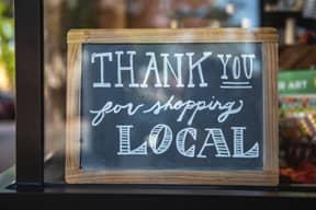 A chalkboard sign in a shop window reading "Thank you for shopping local"